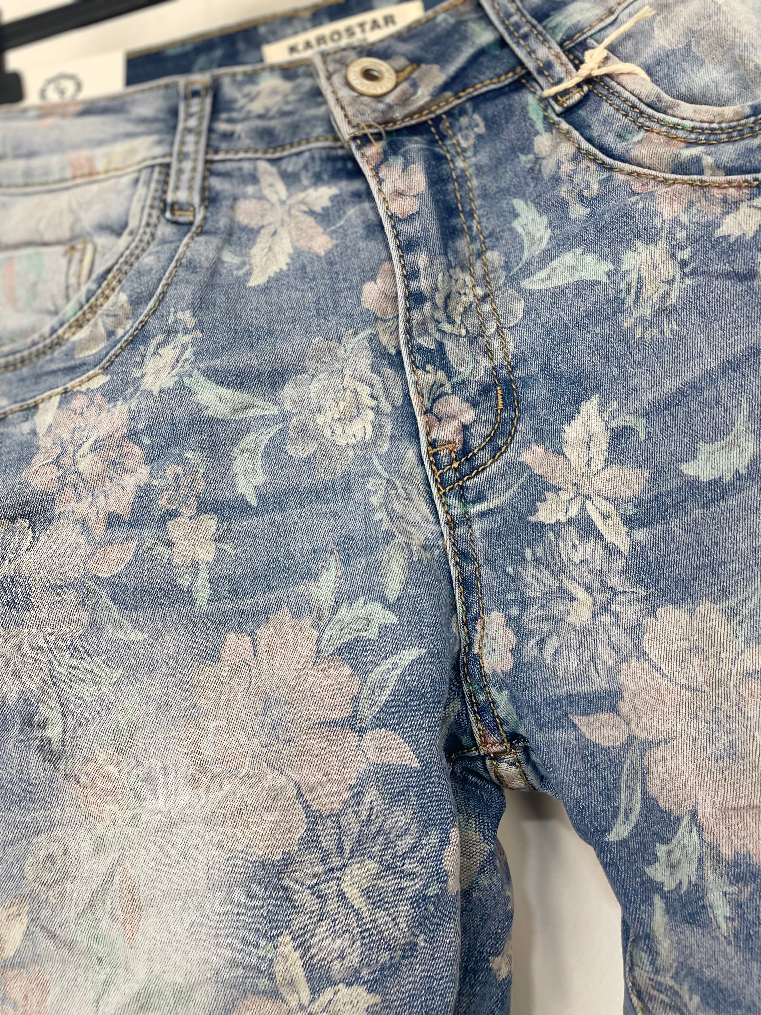 Jean stretch bleu clair motif floral, tombé ajusté aux chevilles, porté avec sneakers blanches minimalistes