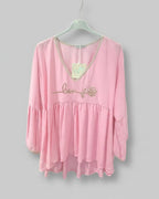 Vue sur cintre de la blouse rose Mams'ailes montrant la coupe asymétrique plus longue à l'arrière pour un tombé parfait sur les hanches.