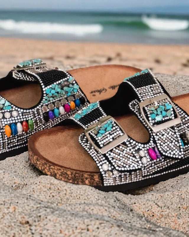 Détail strass brillants et pierres colorées sur mules bohème noires avec brides ajustables