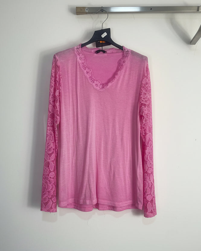 Top rose vif en dentelle ajourée, mis en valeur par une lumière naturelle douce