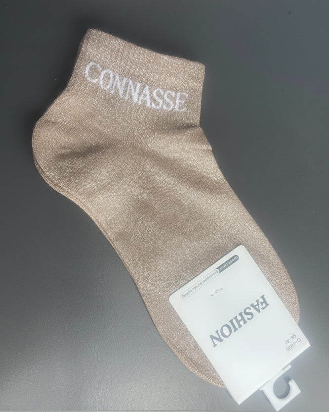 Chaussette beige-dorée à effet lurex et message "Connasse" – parfaite pour briller sans filtre.