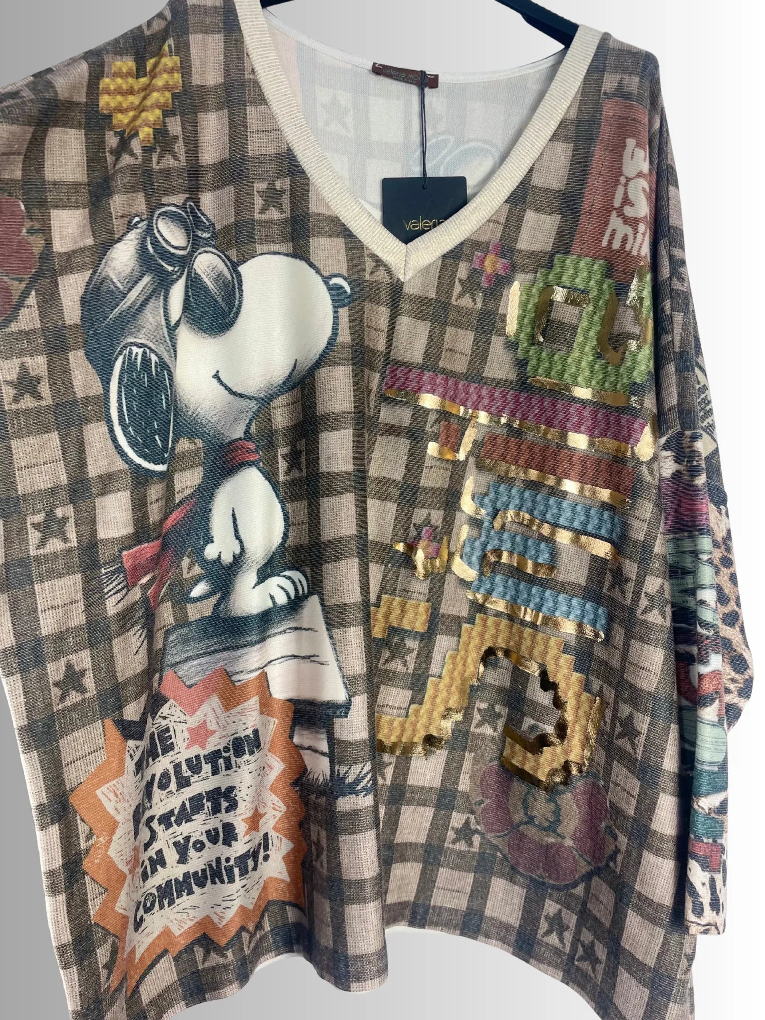 Femme portant un pull oversize Snoopy beige à motif vintage dans un salon lumineux.