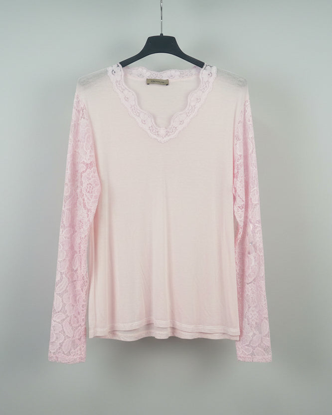 Top rose pâle en dentelle ajourée, look doux et féminin, mi-corps femme souriante