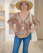 Look complet : blouse bohème à pompons, jean bleu flare et chapeau de paille pour une tenue de printemps ensoleillée.