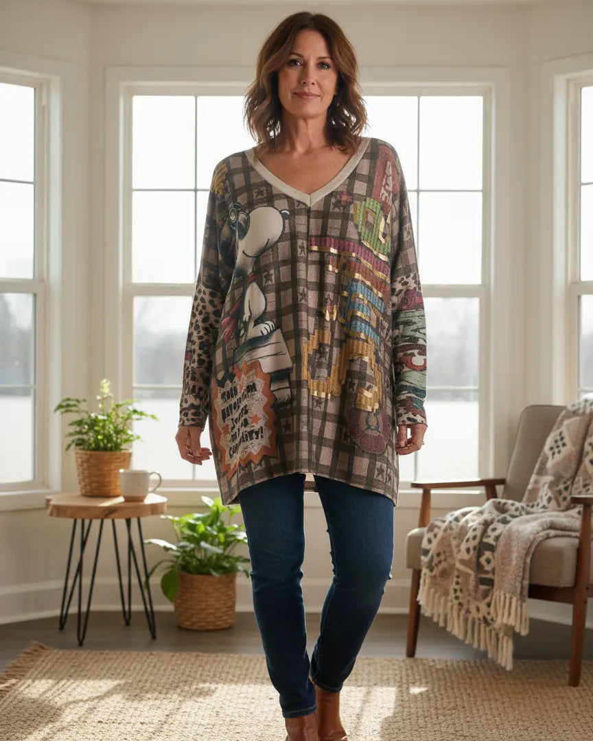 Femme portant un pull oversize Snoopy beige à motif vintage dans un salon lumineux.