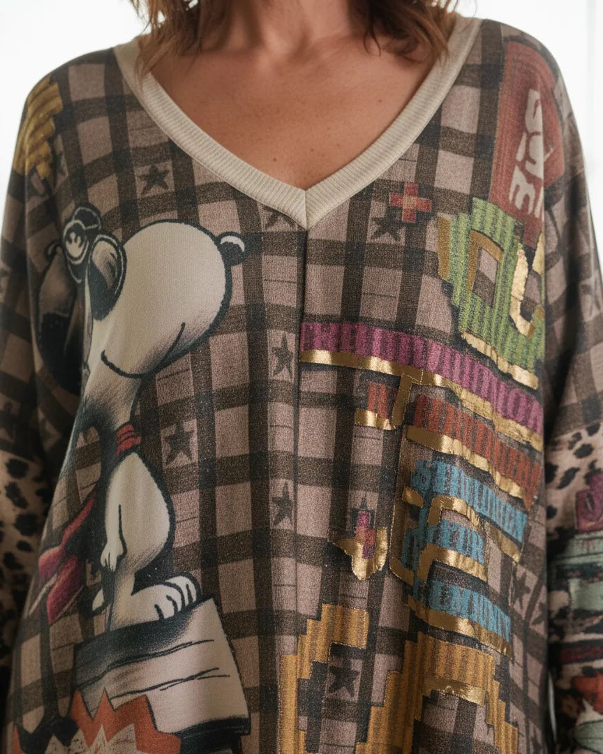 Femme portant un pull oversize Snoopy beige à motif vintage dans un salon lumineux.