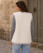     Vue de dos du gilet Livigno en fausse fourrure blanche porté par une femme dans une ruelle italienne