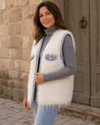     Femme portant le gilet Livigno en fausse fourrure blanche vu de trois quarts devant une porte ancienne en Italie