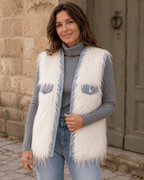     Femme portant le gilet Livigno en fausse fourrure blanche avec col roulé gris et jean clair dans une ruelle italienne