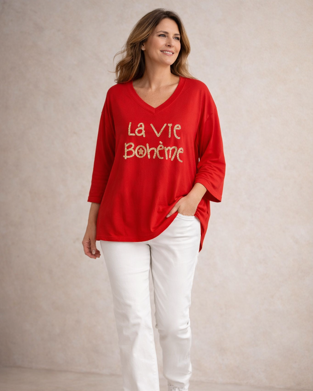 Pull rouge femme col V La Vie Bohème doré, porté avec pantalon blanc chic