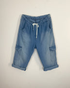 Bermuda cargo denim bleu clair à taille élastiquée cordon blanc et poches cargo latérales, revers bas de jambe, vue flatlay de face fond blanc