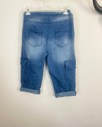 Dos du bermuda cargo denim bleu moyen, deux poches arrière passepoilées et poches cargo latérales, taille élastiquée, revers bas de jambe, vue de dos sur cintre