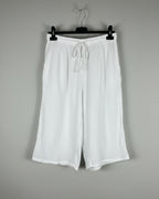 Bermuda gaze de coton blanc sur cintre, silhouette évasée et légère, taille élastique avec cordon