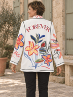 Dos du blazer Forever porté, avec grande inscription colorée et fleurs sur fond blanc.