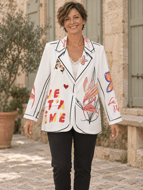 Femme portant le blazer blanc Forever boutonné, avec fleurs, papillons et pantalon noir.