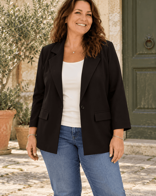 Eva portant le blazer noir LOVE ouvert sur un haut écru et un jean