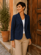Femme portant le Blazer Siena en denim stretch bleu en vue trois quarts avec pantalon camel dans une ruelle italienne