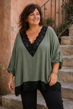 Femme taille 48/50 portant la blouse Siena kaki à dentelle noire avec un Pantalon Magique noir dans un escalier italien