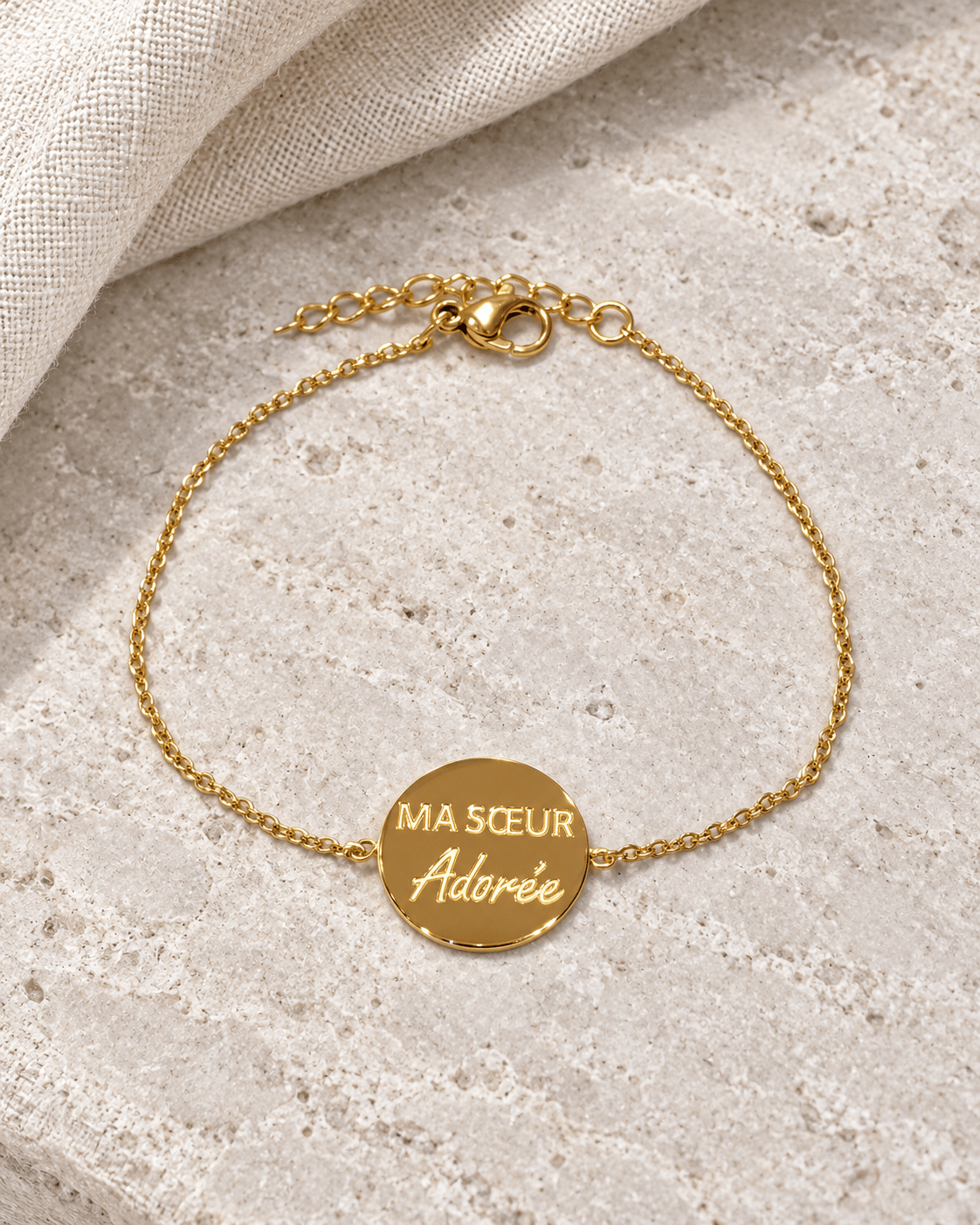 Vue retouchée du bracelet doré Ma sœur adorée, gravure et chaîne sur pierre claire.