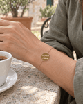 Bracelet doré Ma sœur adorée porté au poignet, vue rapprochée.