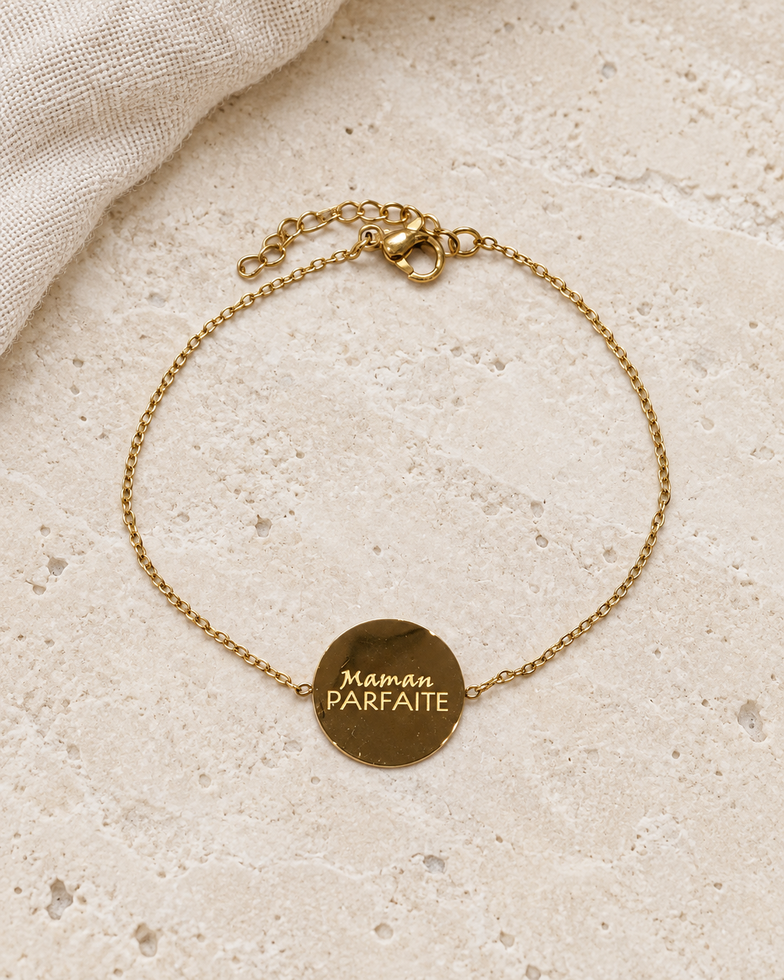 Vue retouchée du bracelet doré Maman parfaite, gravure et chaîne sur pierre claire.