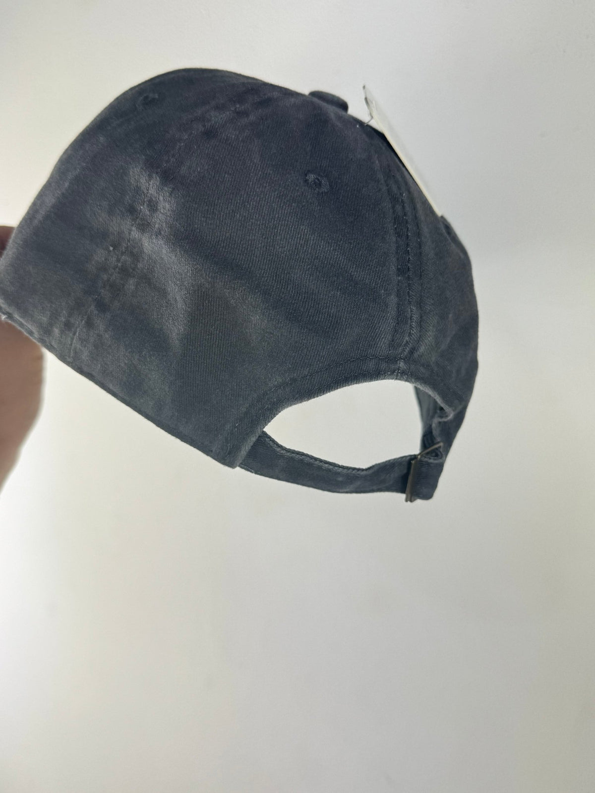 Arrière de la casquette en jean gris délavé, patte réglable et boucle métallique.