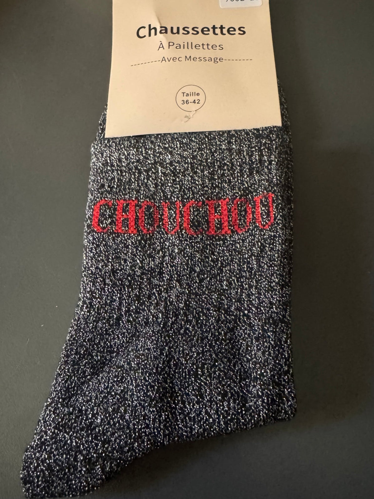 Détail des chaussettes CHOUCHOU noires, de leur maille pailletée et du message rouge.