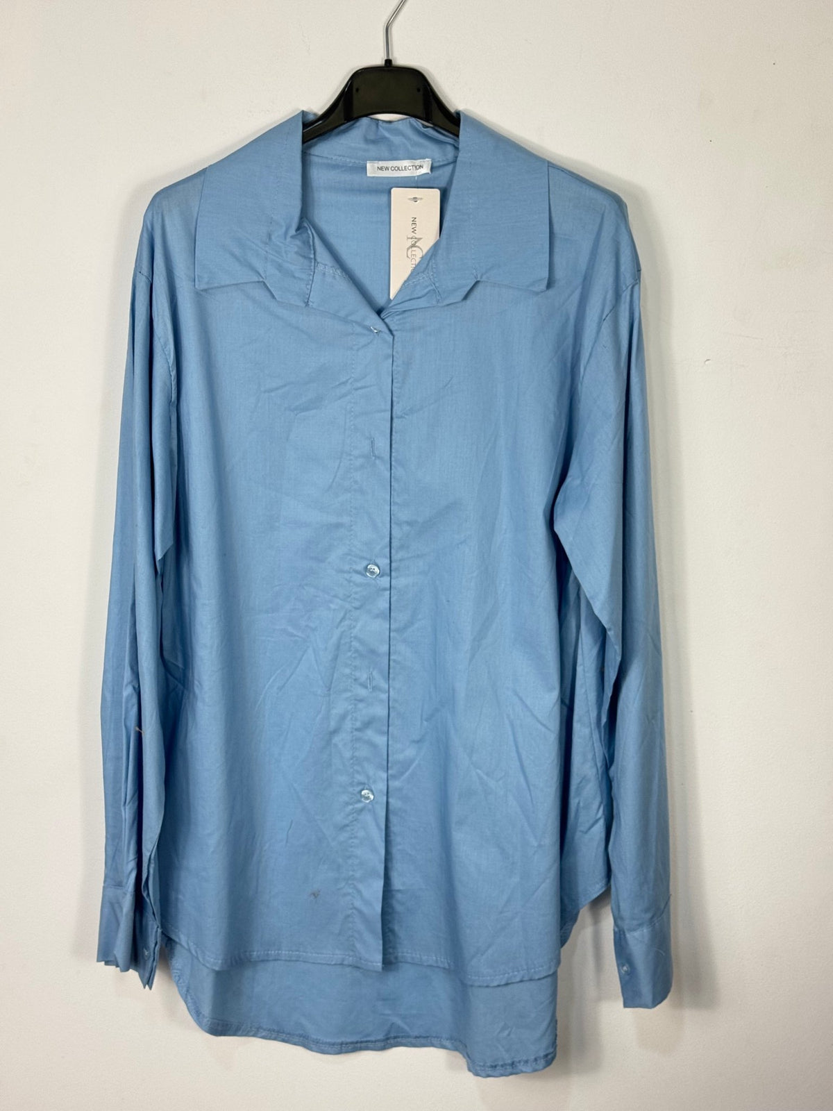 Chemise bleue en coton sur cintre avec son bas arrondi.