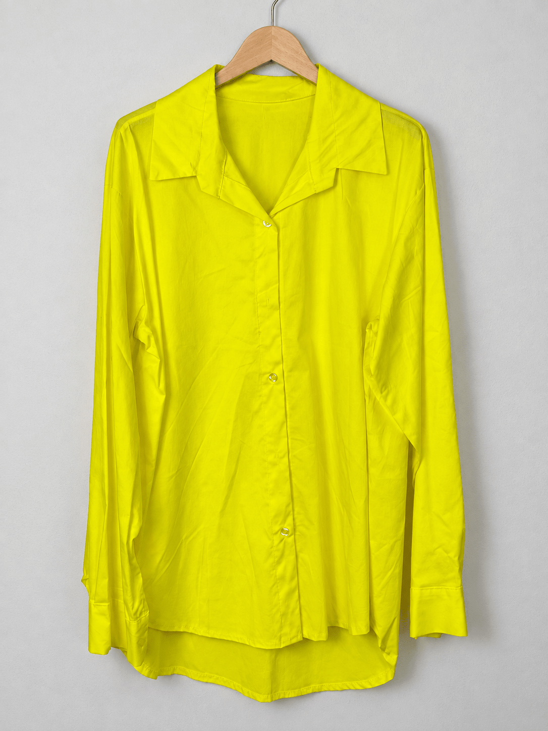 Chemise jaune unie sur cintre, col ouvert, manches longues et bas arrondi.