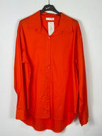 Chemise orange en coton sur cintre, col ouvert et manches longues.