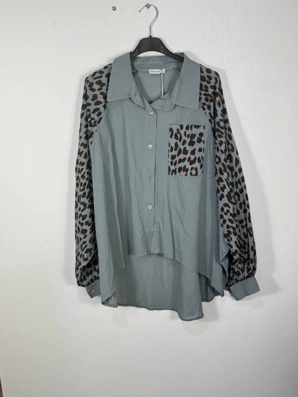 Chemise bleu gris sur cintre, avec manches et poche léopard.