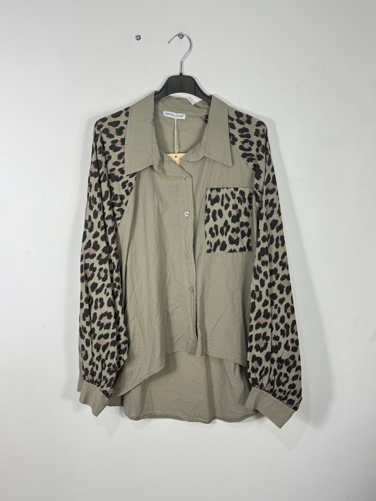 Chemise taupe photographiée sur cintre, manches longues et poche poitrine léopard, col uni et dos plus long.