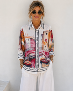 Femme portant une chemise aspect lin imprimée pont et canal rose style italien avec pantalon palazzo blanc