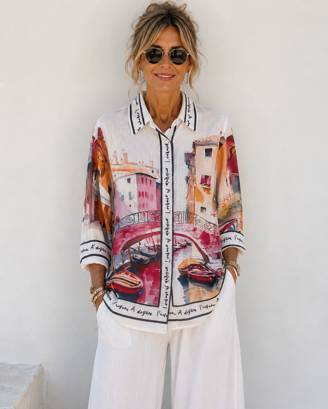Femme portant une chemise aspect lin imprimée pont et canal rose style italien avec pantalon palazzo blanc
