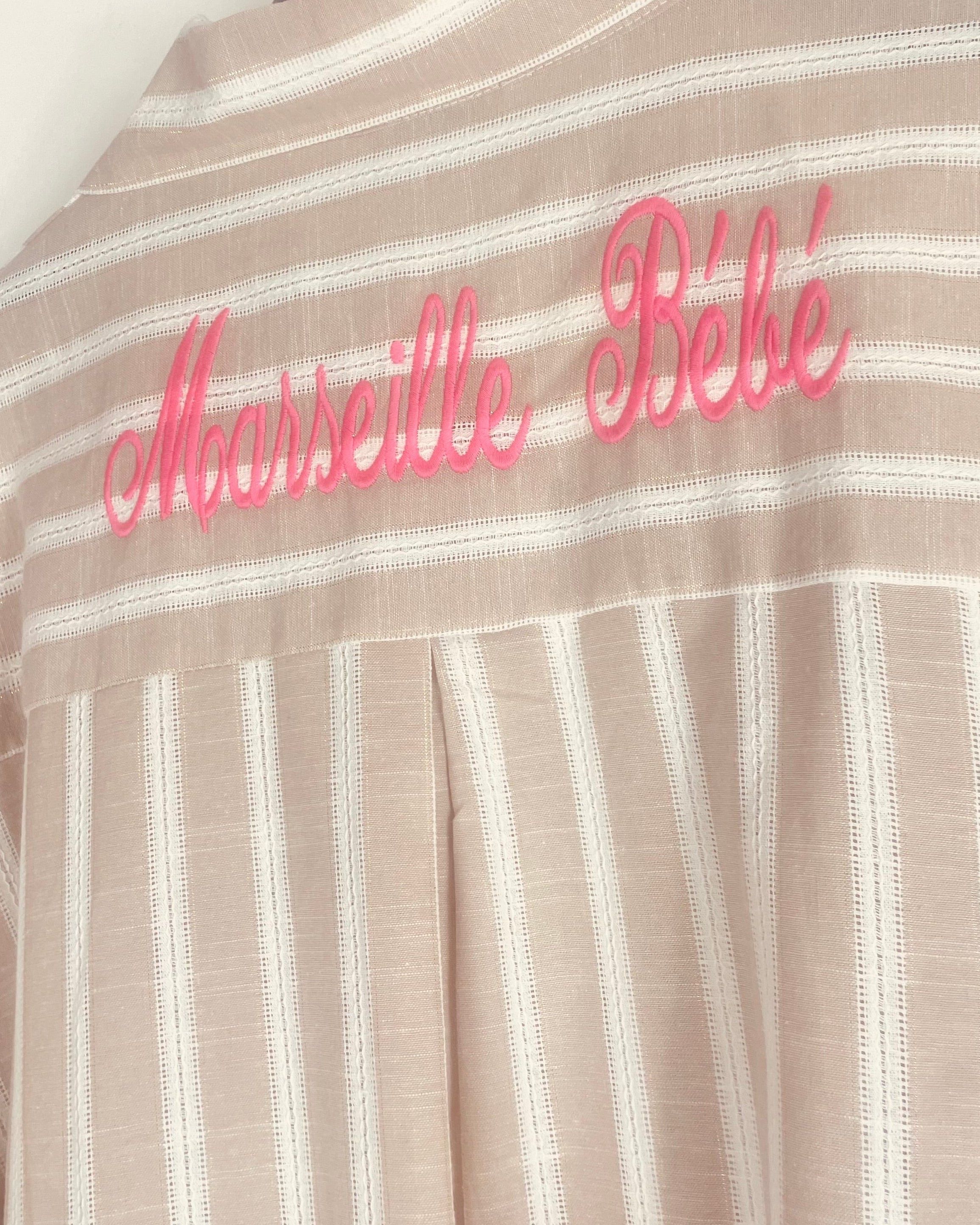 Zoom broderie rose fluo Marseille bébé au dos d’une chemise longue bohème rayée