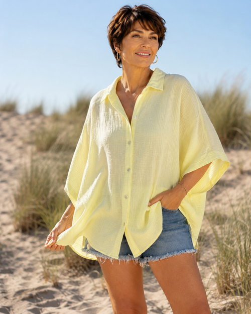 Femme portant une chemise oversize jaune en gaze de coton avec un short en jean