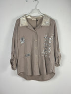 Chemise taupe de face sur cintre, avec cinq boutons et un col effet serpent métallisé.