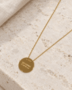 Vue retouchée du collier doré Les copines c’est la vie, gravure et chaîne sur pierre claire.
