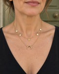 Collier doré double rang porté au décolleté, cinq pastilles et croissant de lune.