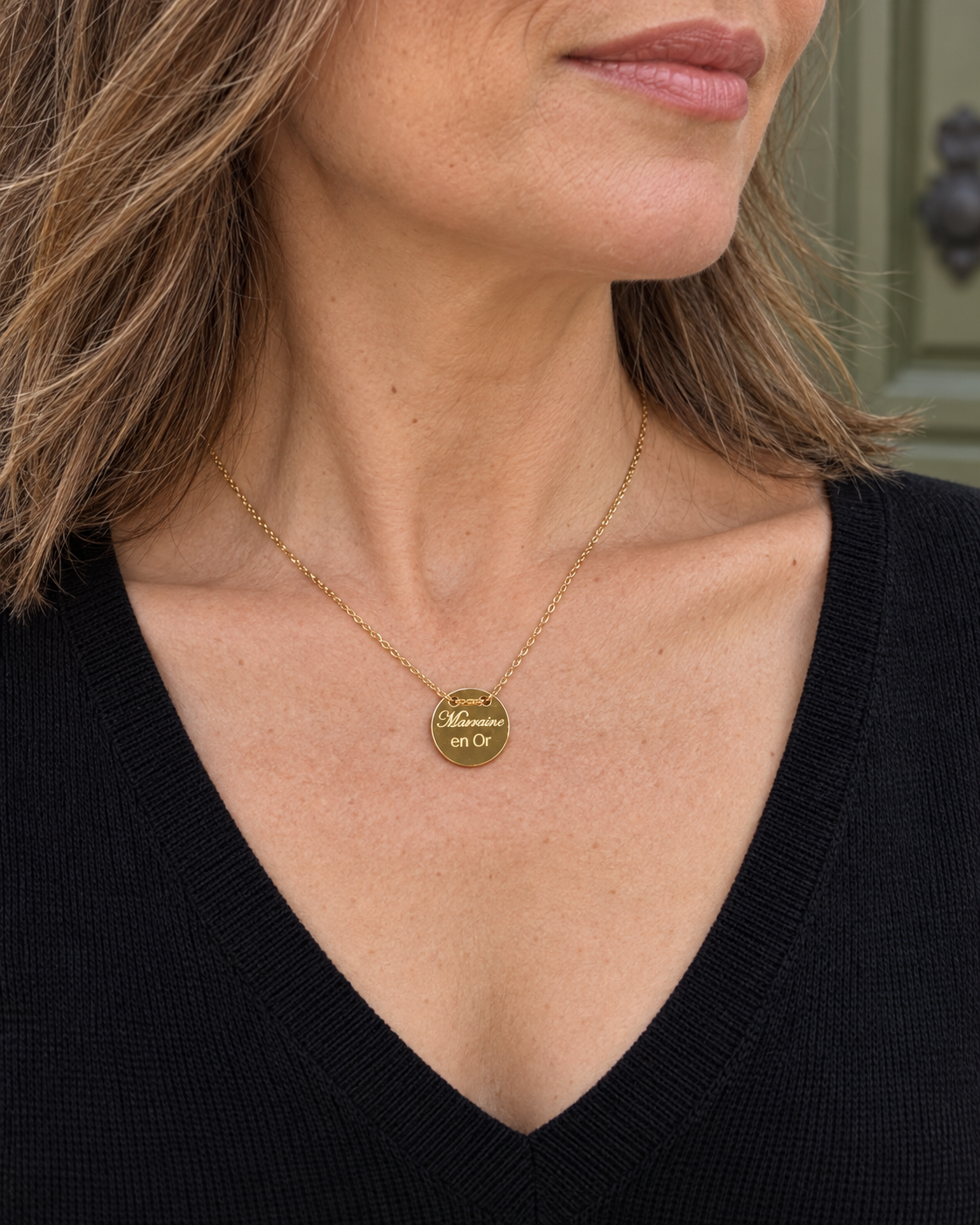 Collier doré Marraine en or porté avec un col V noir.