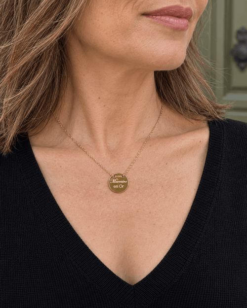Collier doré Marraine en or porté avec un col V noir.