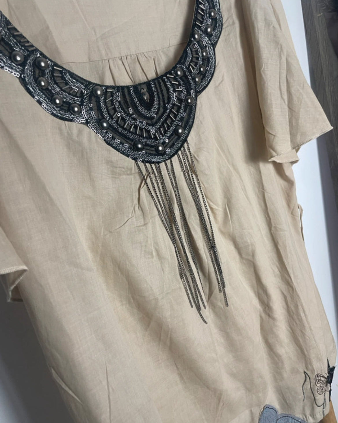 Détails Blouse fluide en coton beige avec col brodé de sequins et chaînettes, longueur 60 cm.