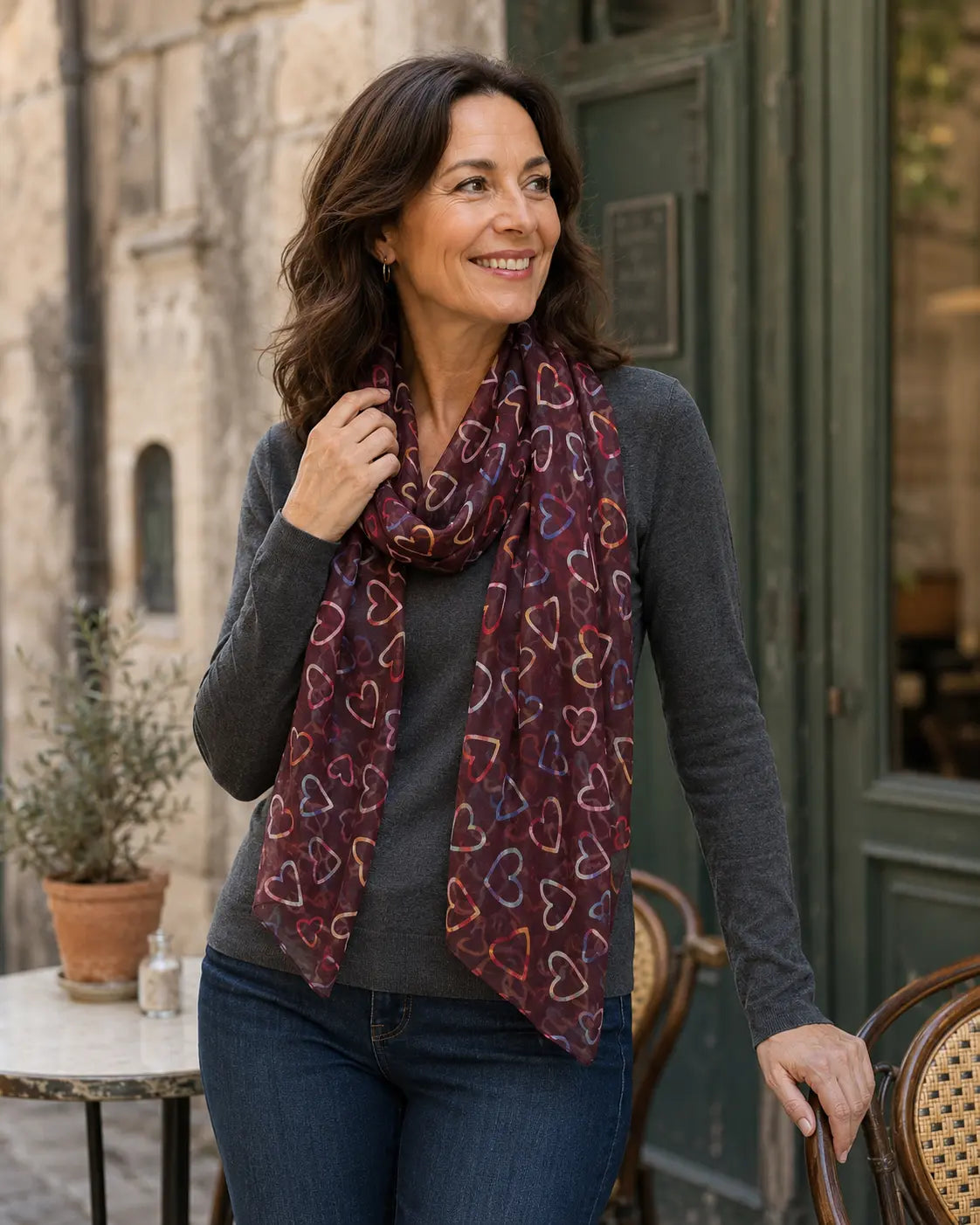 Femme portant le foulard Batticuore bordeaux à cœurs multicolores avec un tour souple autour du cou
