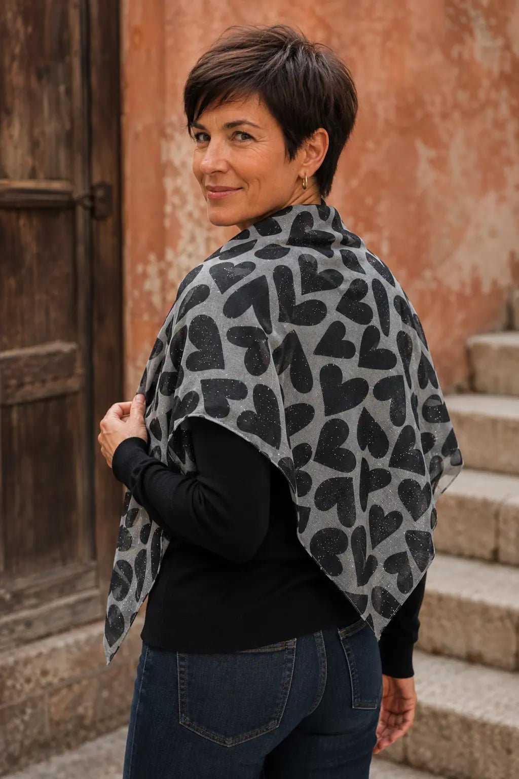 Femme portant le foulard Cuori gris à cœurs pailletés drapé sur les épaules