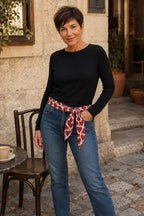 Femme portant le foulard Cuori rouge et blanc noué en ceinture sur un jean