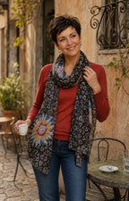 Femme portant le foulard Fiora noir à fleurs colorées et petits cœurs avec un tour souple autour du cou