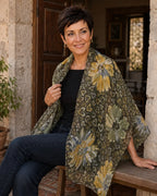 Femme portant le foulard Fiora vert à fleurs jaunes et petits cœurs, largement drapé sur les épaules