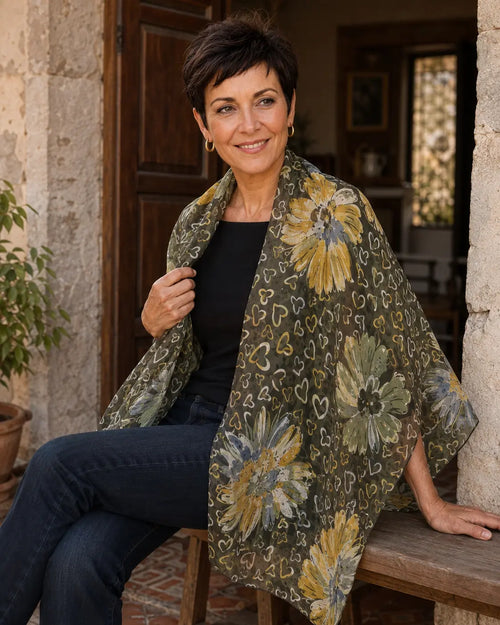 Femme portant le foulard Fiora vert à fleurs jaunes et petits cœurs, largement drapé sur les épaules