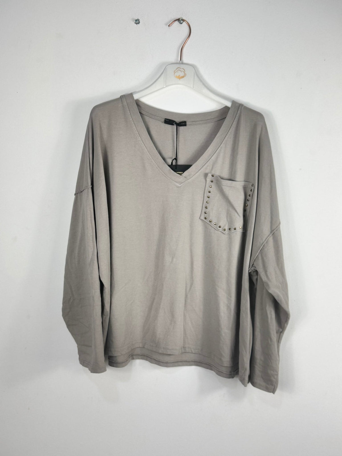 Haut taupe grisé sur cintre, col V et poche poitrine bordée de clous.