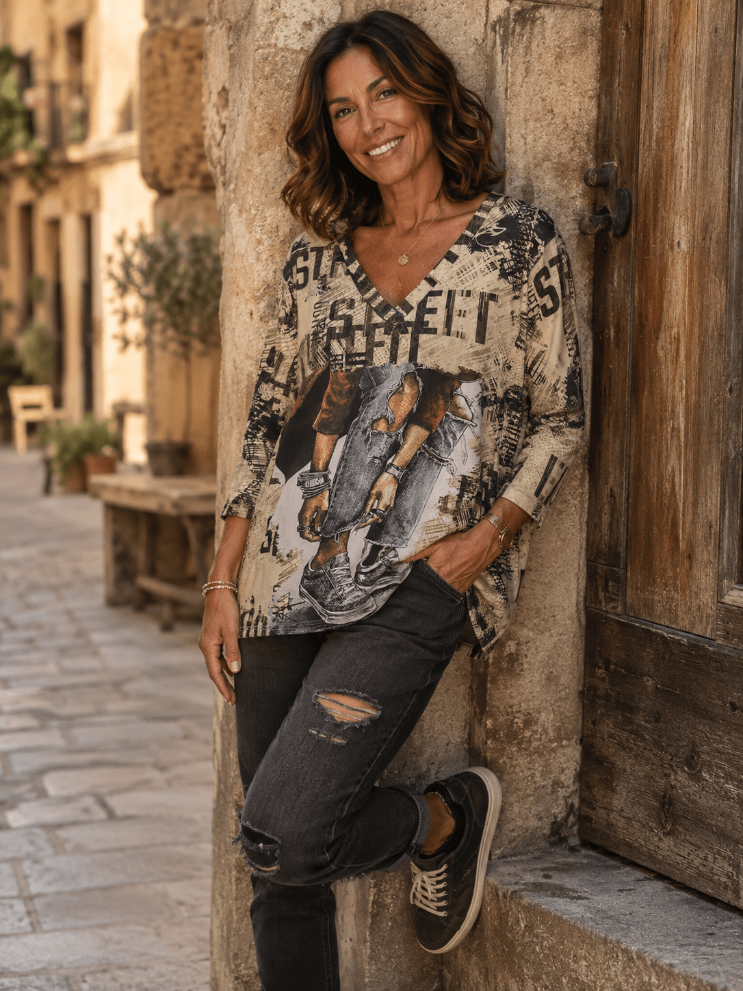 Femme portant le haut Stella Girl Street beige imprimé avec jean gris dans une ruelle italienne